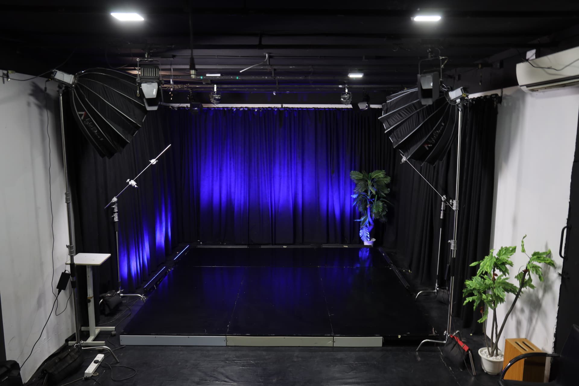 Studio B shooting floor with lighting rig, blue stage wash and softboxes