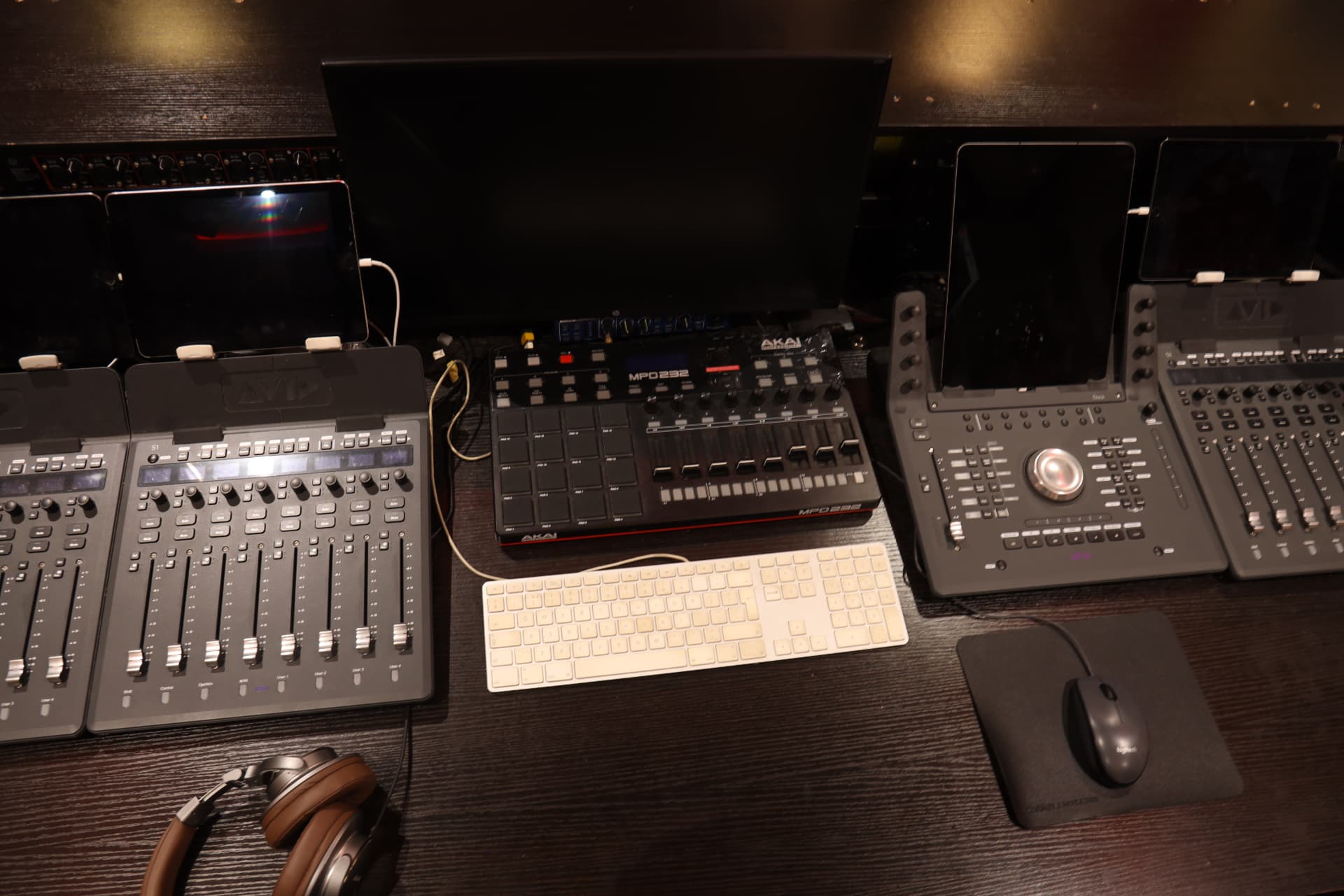 Close-up of the Sound Suite 1 desk with Avid fader controllers, Akai pad controller, keyboard and headphones