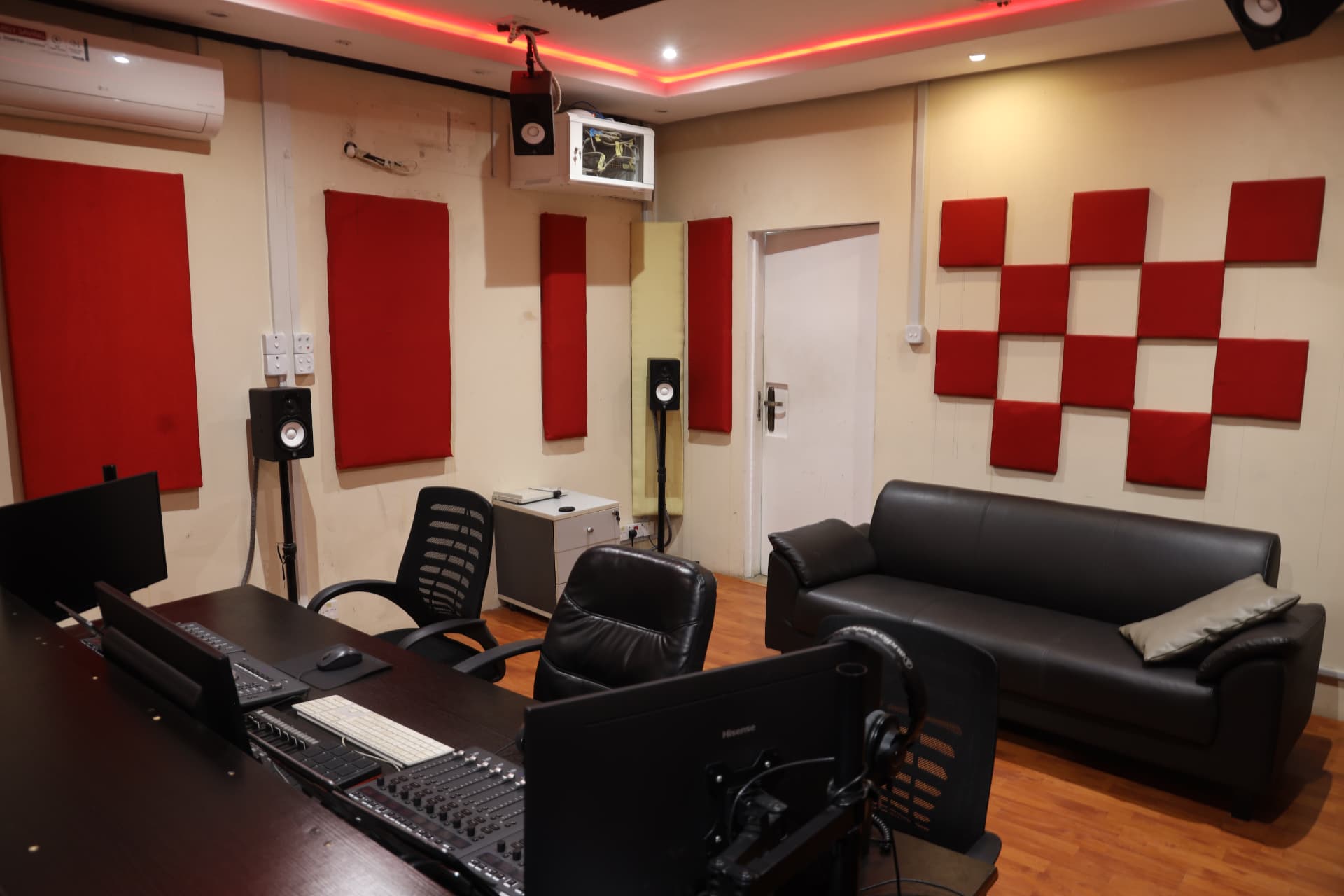 Sound Suite 1 control room with mixing console, leather sofa and red acoustic panels