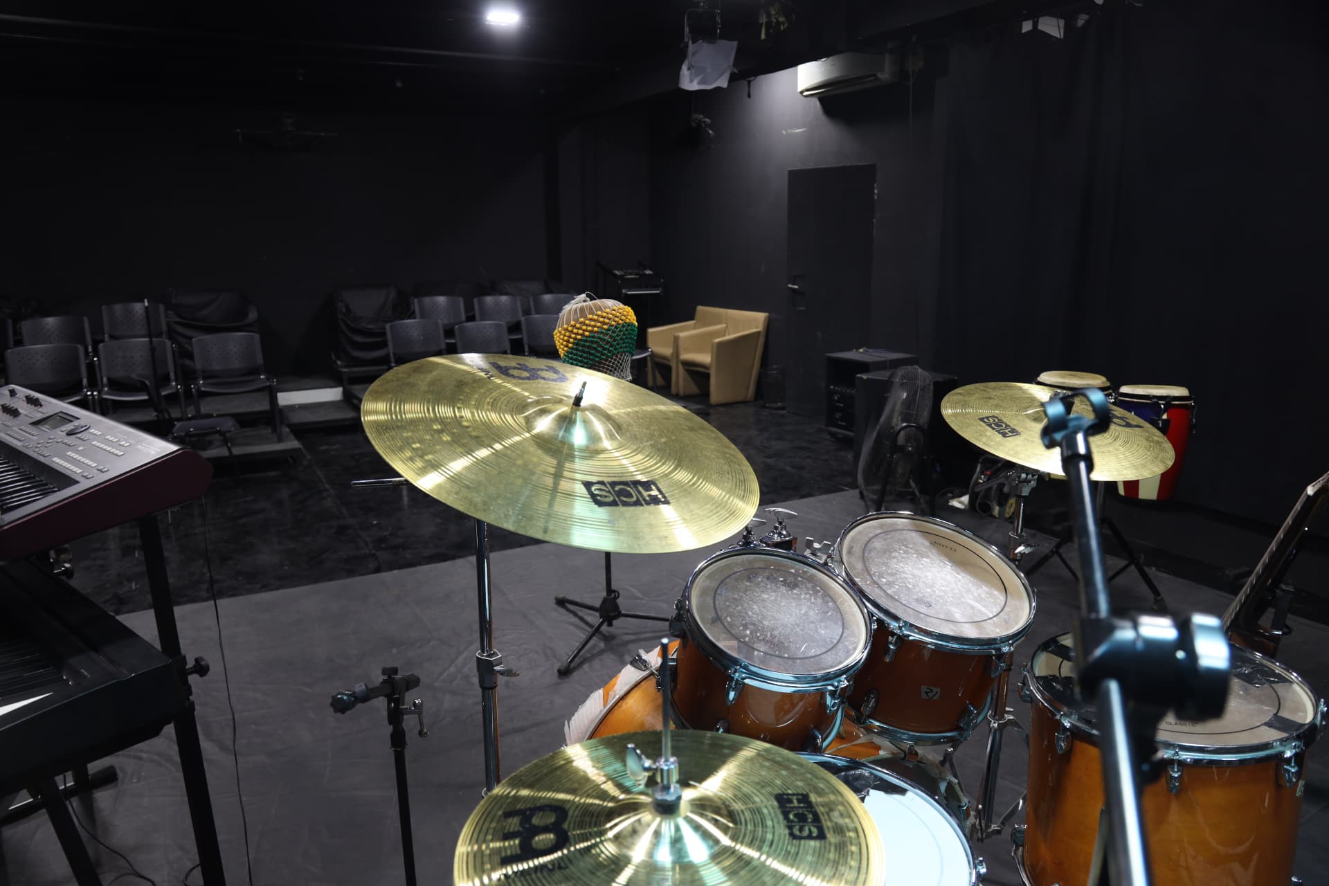 Studio floor liveband recording space from the drummer's view, showing drum kit, keyboard stand, shekere and conga drums
